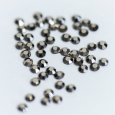 Rozsypane ciemne metaliczne kryształki Dark Chrome na jasnym tle