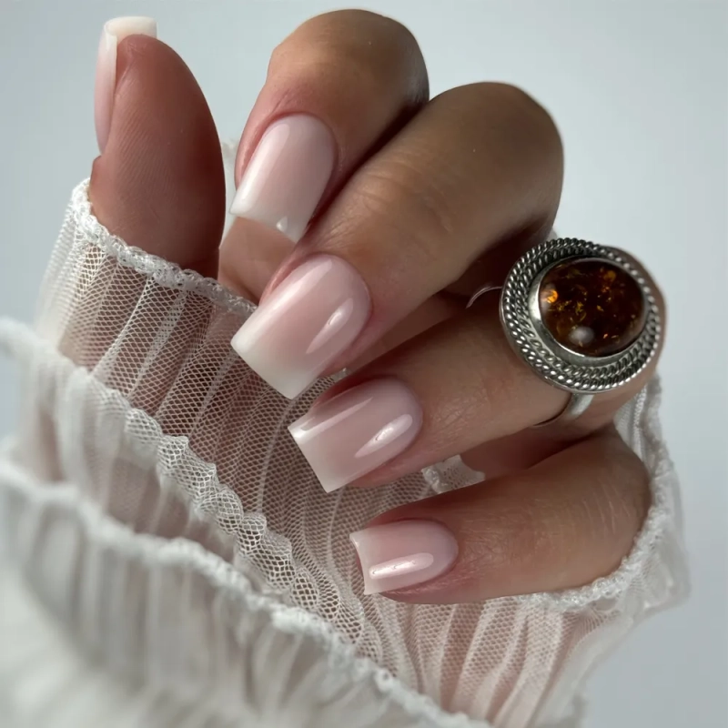 Dłoń z kwadratowymi mlecznoróżowymi paznokciami i pierścionkiem – żel Tixy Cover Petit Pink