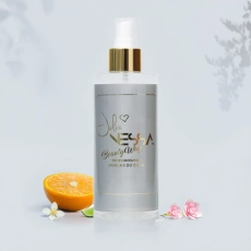 Butelka perfumowanej mgiełki do ciała Beauty Way na szarym tle z pomarańczą i kwiatami