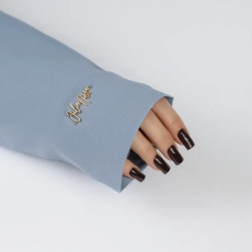 Dłoń z ciemnobrązowymi paznokciami w rękawie do zdjęć – marynarka baby blue