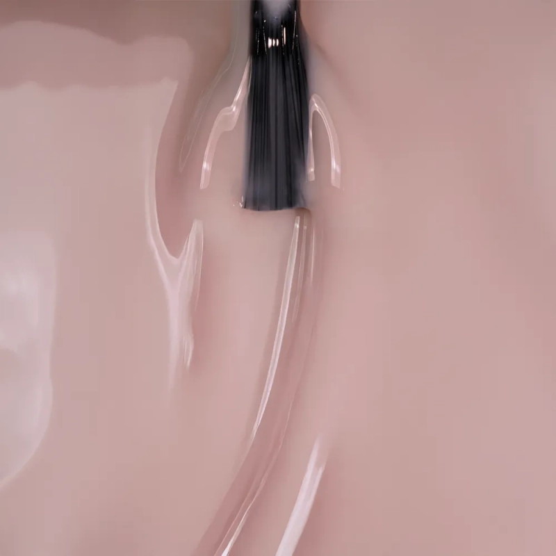 Baza hybrydowa Rubber Base Natural – pędzelek w beżoworóżowej masie w zbliżeniu