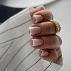 Stylizacja paznokci z babyboomerem wykonanym akrylożelem milky oraz blush. Na ręce założony rękaw od marynarki w paski