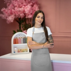 Stylistka w szarym fartuszku kosmetycznym z logo Julia Nessa