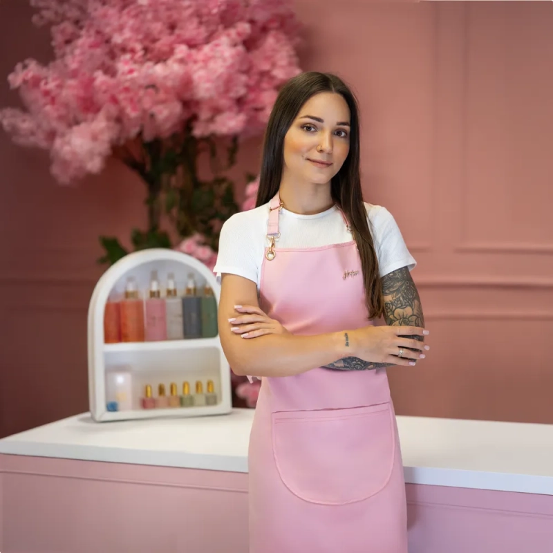 Stylistka w fartuszku kosmetycznym w kolorze pudrowy róż z logo Julia Nessa