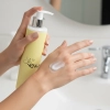 Dłoń z porcją perfumowanego balsamu do ciała Blossom Soul nad umywalką