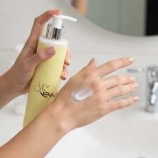 Dłoń z porcją perfumowanego balsamu do ciała Blossom Soul nad umywalką