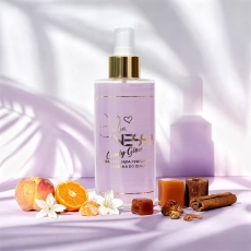 Candy Glow perfumowana mgiełka do ciała 250 ml Julia Nessa na tle jasnej powierzchni, otoczona owocami, karmelami i cynamonem, z widoczną złotą etykietą